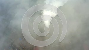 Smoke from a power station chimney rising from a low, creeping fog. Drone view