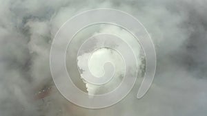 Smoke from a power station chimney rising from a low, creeping fog. Drone view