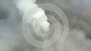 Smoke from a power station chimney rising from a low, creeping fog. Drone view