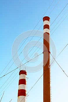 Smoke from a red and white chimney on blue sky background.