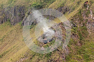 Smoke rises from a volcanic flue in the Batur Crater. Geological formation in active volcano with volcanic chimney.