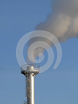 Smoke spews out of a chimney at an industrial plant photo