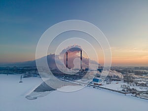 Smoke stacks over sunrise sky background at freezing weather morning with haze