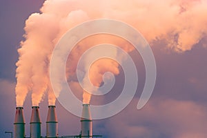 Smoke and steam rising into the air from power plant stacks; dark clouds background; concept for environmental pollution and