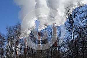 Smoke from Three pipes CHP against the background of trees at Moscow, Russia