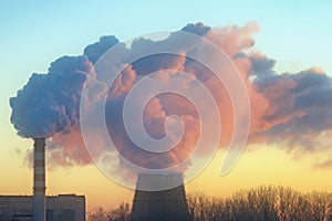 Smoke from two factory chimneys in the light of the setting sun.