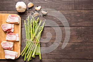 Smoked bacon with fresh asparagus on wooden background