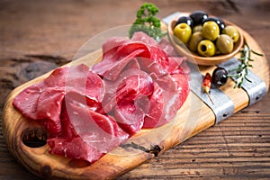 Smoked beef prosciutto, sliced bresaola on a wooden board photo