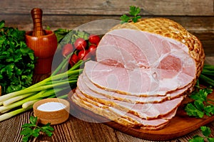 Smoked boneless ham with vegetables and salt on wooden table
