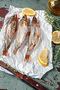 Smoked capelin and smelt on white paper close-up with lemon and fragrant herbs
