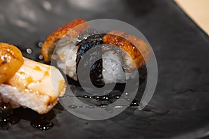 Smoked eel sushi on black dish. Japanese food