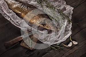 Smoked fish with bread and damask knife on the wood table