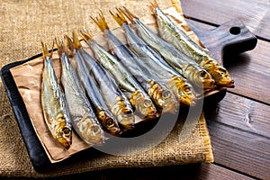 Smoked fish on a wooden cutting board on a dark wooden table. Close up.