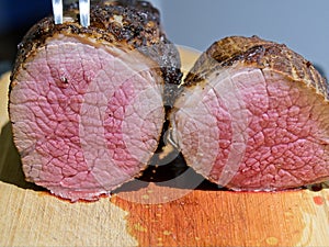 Smoked and grilled beef eye of round cut in half to show medium rare pink