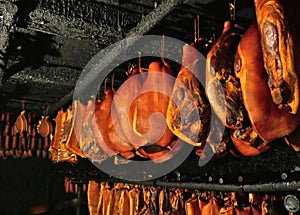 Smoked ham, bacon and sausages hang on hooks in a smokehouse in Germany, Schleswig-Holstein