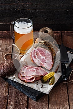 Smoked ham with rye bread, pickles and beer, rustic style