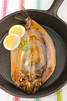 Smoked kipper with lemon and parsley in a pan