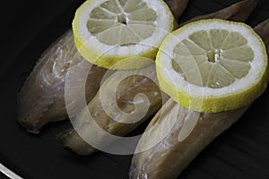 Smoked mackerel fillets with lemon in a griddle frying pan prepared for cooking