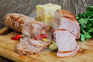 Smoked meat, cheese, herbs on a wooden board