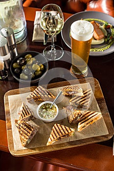 Smoked meat sandwich and glass of beer on wooden table at restaurant