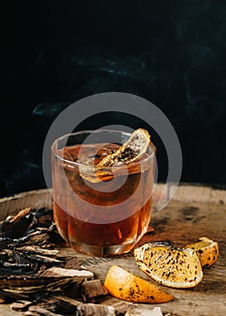 Smoked old fashioned cocktail on dark wooden background