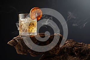 Smoked old fashioned cocktail with ice and dried orange slice