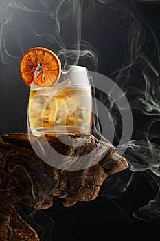 Smoked old fashioned cocktail with ice and dried orange slice