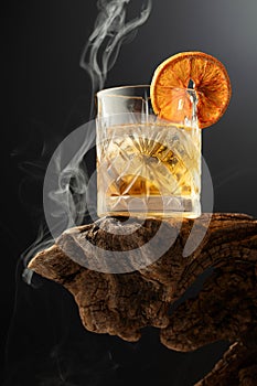 Smoked old fashioned cocktail with ice and dried orange slice