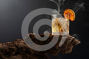 Smoked old fashioned cocktail with ice and dried orange slice