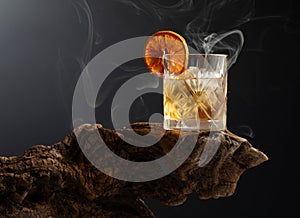 Smoked old fashioned cocktail with ice and dried orange slice