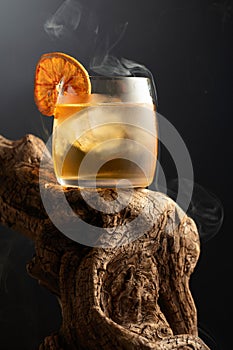 Smoked old fashioned cocktail with ice and dried orange slice
