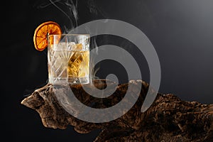 Smoked old fashioned cocktail with ice and dried orange slice