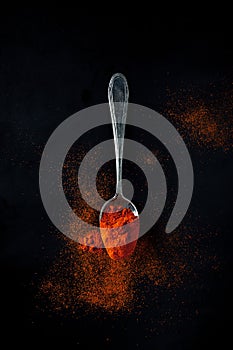 Smoked paprika, spicy, sweet on a teaspoon on a black background