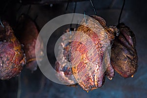 Smoked pork meat in smoker on dark background.