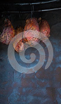 Smoked pork meat in smoker on dark background.