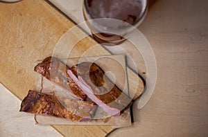 Smoked pork ribs with a glass of beer on a cutting board