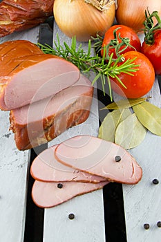 Smoked pork tenderloin with vegetables. Sliced meat. Meat on the crate.