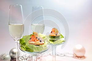 Smoked salmon appetizer with caviar and lettuce in glasses, two champagne flutes and holiday decoration, festive party snack, copy