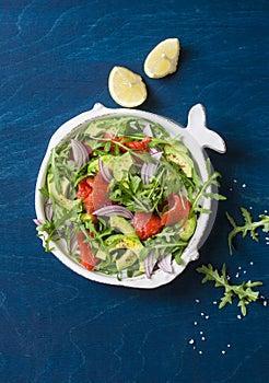 Smoked salmon, avocado, arugula, red onion salad. Healthy snacking on blue background