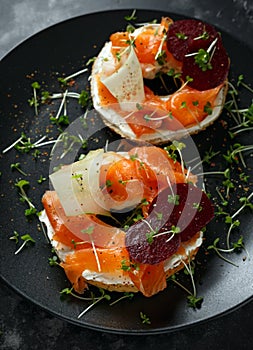 Smoked salmon bagel toasts with soft cheese, cucumber ribbons and beetroot and dill, cress salad