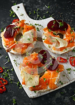 Smoked salmon bagel toasts with soft cheese, cucumber ribbons and beetroot and dill, cress salad