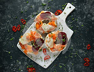 Smoked salmon bagel toasts with soft cheese, cucumber ribbons and beetroot and dill, cress salad