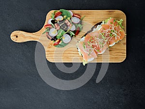 Smoked salmon bruschetta and salad on a wonden board