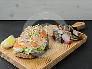 Smoked salmon bruschetta and salad on a wonden board