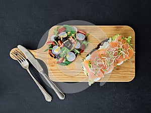 Smoked salmon bruschetta and salad on a wonden board