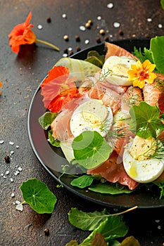 Smoked salmon and cucumber salad with nasturtium leaves and edible flowers. healthy food