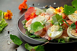 Smoked salmon and cucumber salad with nasturtium leaves and edible flowers. healthy food