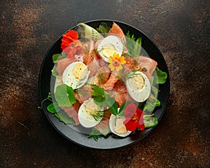 Smoked salmon and cucumber salad with nasturtium leaves and edible flowers. healthy food