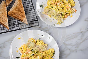 Smoked salmon with scrambled eggs, whole grain bread toast and dill on marble background