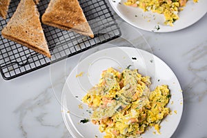 Smoked salmon with scrambled eggs, whole grain bread toast and dill on marble background